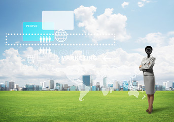 Camera headed woman standing on green grass against modern cityscape