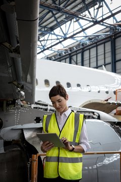 Female aircraft maintenance engineer using digital tablet