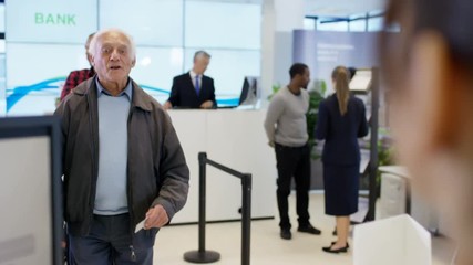 Worker at customer service desk assisting senior customer in modern bank