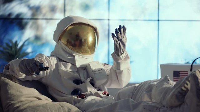  Astronaut in full suit relaxing in apartment, watching TV & channel surfing
