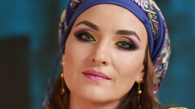 Beautiful arabian girl in national makeup, blue studio backgraund. Clouse up 