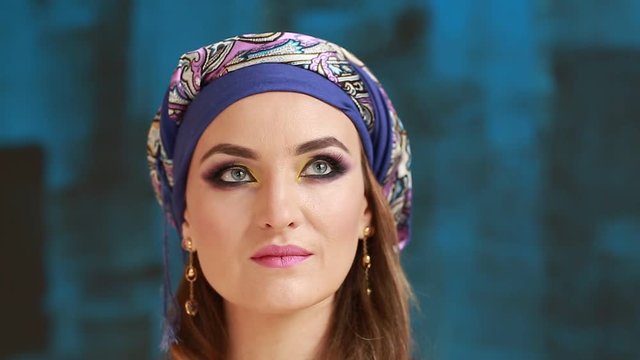 Beautiful arabian girl in national makeup, blue studio backgraund. Clouse up 