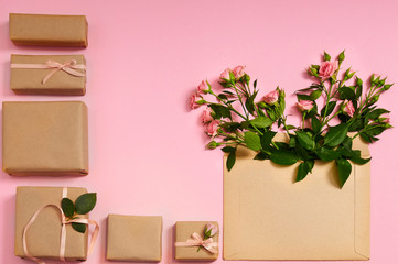 Flowers composition. Gifts boxes and heart shaped rose flowers in envelope on pink background. Flat lay, top view.