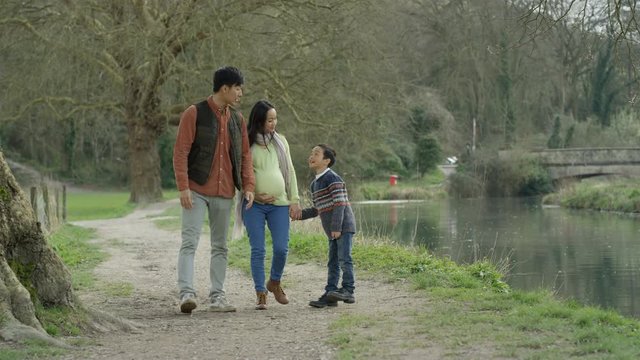  Happy family walking in the country, parents expecting baby with little boy
