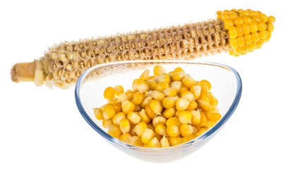 Yellow boiled corn isolated on white background. Partly eaten corncob and pile of corn grains in glass bowl.