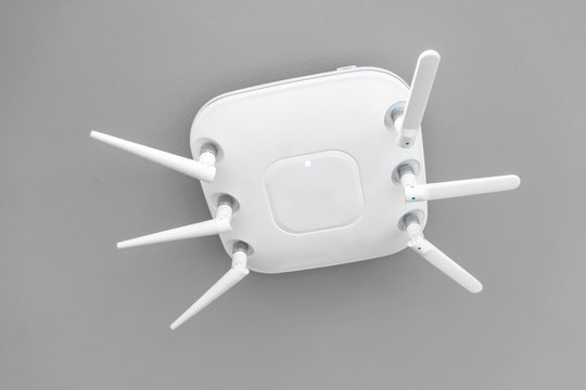 Wireless router for network hanging on white ceiling.