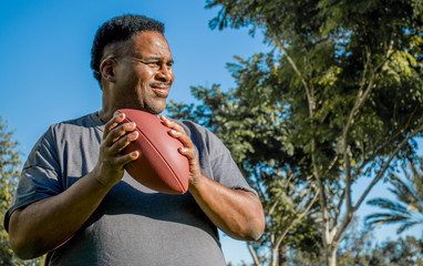 medium profile of middle aged black man catching football 