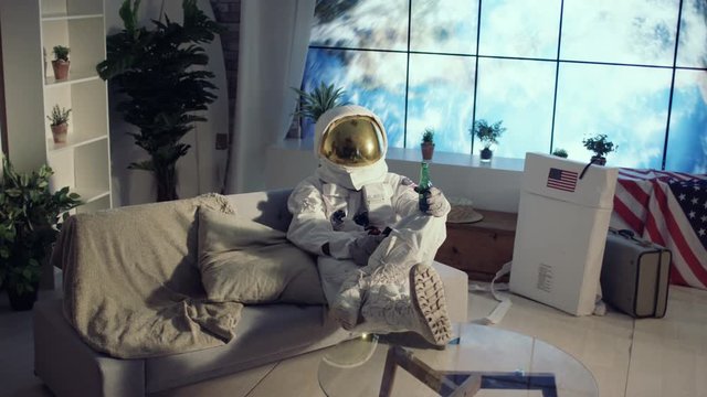 Astronaut relaxing in apartment, watching TV & drinking a beer