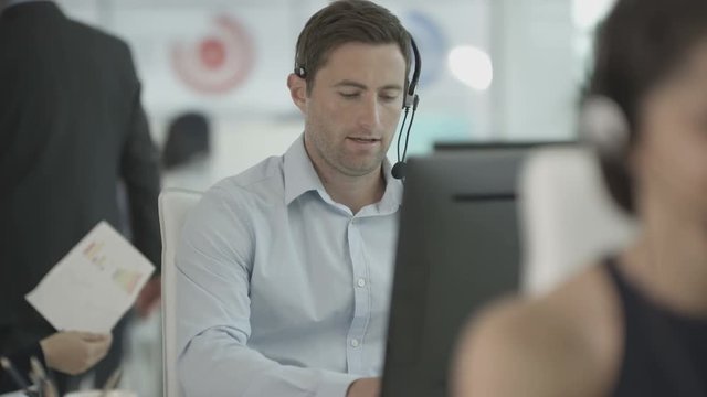  Friendly customer service operator talking to customer in busy call centre
