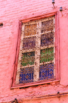 Windows made up of colourful glass covered by metal grilles on a house in the Medina in Marrakech, Morocco