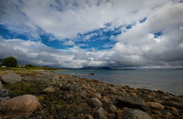 Seascape with stones on the shore and white clouds