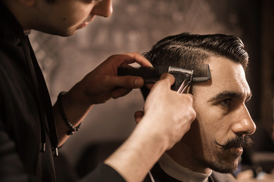 close up of barber working on client hair in barber shop - Powered by Adobe