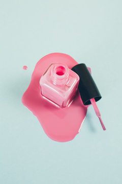 Pink Nail Polish Bottle In Puddle Of Nail Polish Liquid.