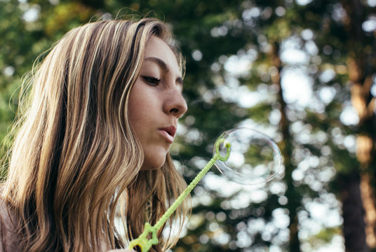 Beautiful teenage girl blowing bubbles