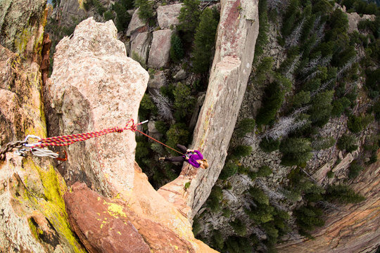 Young Adult Woman Rappels off exposed rock on the Maiden in Colorado