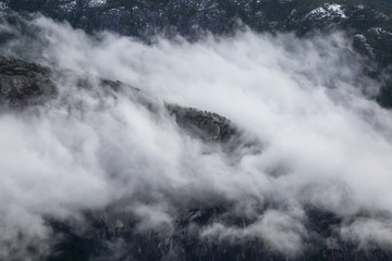 Obraz na płótnie Canvas Aerial View of Chief Mountain Covered in Clouds. Taken in Squamish, British Columbia, Canada, during a cloudy winter morning.