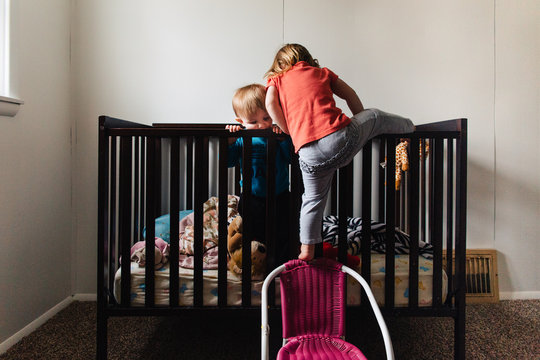 Toddler climbing into crib with sibling
