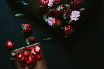Strawberries and flowers on a dark background