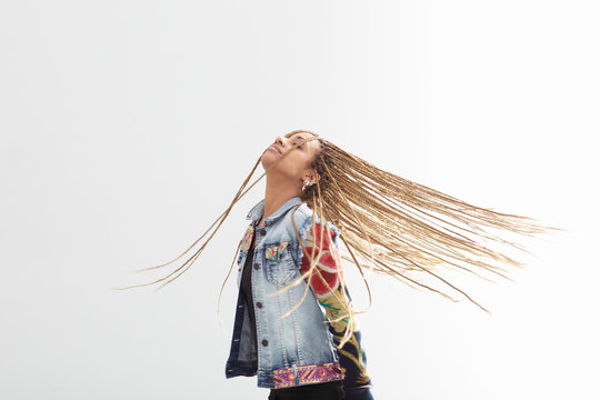 Beautiful young woman with african braids dancing on white background