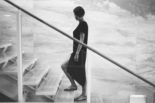 A black and white film portrait of a young beautiful woman on stairs