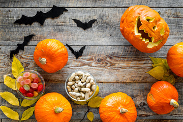 Halloween background. Pumpkins, paper bats and autumn leaves on wooden background top view