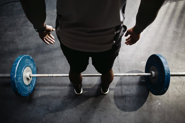 Man standing above ba bell with weights