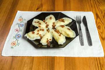 Cooked dumplings with cheese pork scratching on wooden table. Polish, ukrainian, russian traditional food.Fried dumplings with cheese and pork scratching on wooden table.