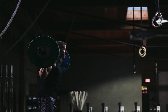 Strong caucasian man lifting weights with chains in gritty workout gym