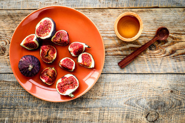 Plate of fresh blue figs and honey on wooden background top view copyspace