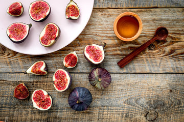Plate of fresh blue figs and honey on wooden background top view copyspace