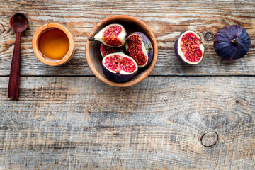 Fresh blue figs in bowl and honey on wooden background top view copyspace