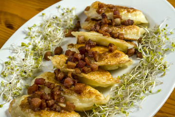 Fried dumplings with cheese and pork scratching on wooden table.