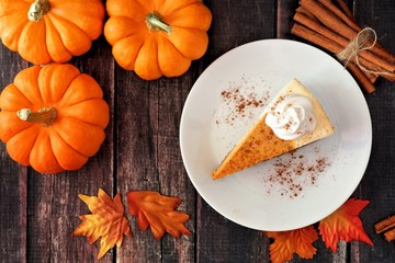 Slice of pumpkin cheesecake with whipped cream, top view on a rustic wooden background © Jenifoto