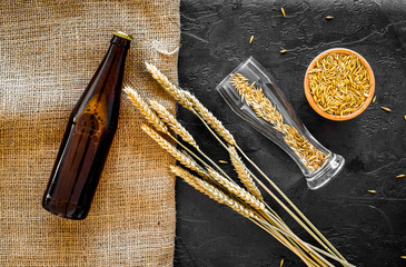 Preparing beer. Barley near beer bottle and glass on black background top view