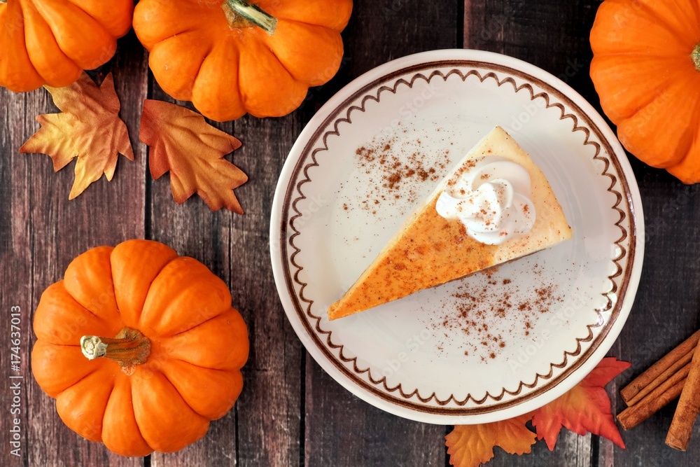 Poster slice of pumpkin cheesecake with whipped cream, overhead table scene on a rustic wood background