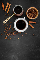 Obraz na płótnie Canvas Brew coffee in turkish coffee pot. Black background top view copyspace