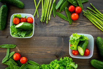 Healthy meal with vegetables tomato, cucumber, asparagus in cotainers on wooden background top view copyspace