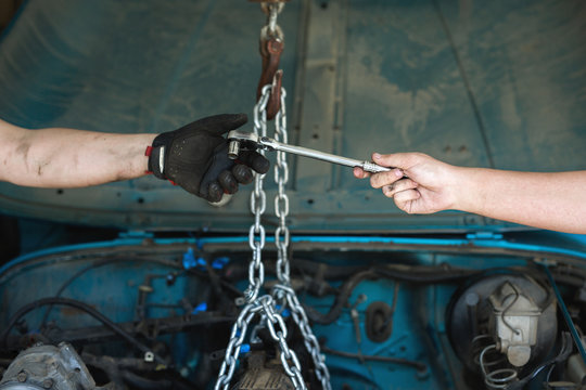 A son handing a socket wrench to his father