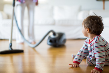 1 year old boy looking his mother doing housework