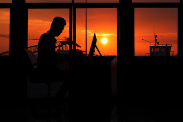 Fototapeta na wymiar Silhouette business man working on a computer with sunset