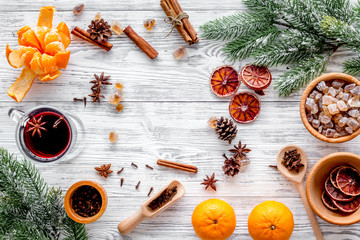 Hot mulled wine or grog cooking for new year celebration with oranges and spices ingredients on light background flat lay