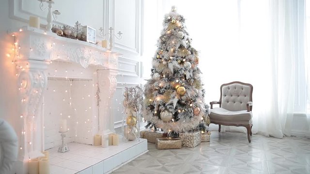 White classic Christmas and New Year interior room with fireplace, green tree decorated and retro grey chair