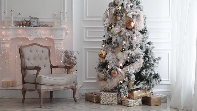 White classic Christmas and New Year interior room with fireplace, green tree decorated and retro grey chair