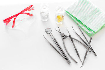 Dentists accessories. Tools, safety glasses and pills on white background copyspace