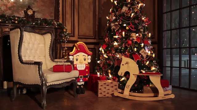 Classic New Year Tree illuminated. Christmas decoration in grunge room interior with fireplace, horse rocking kids chair