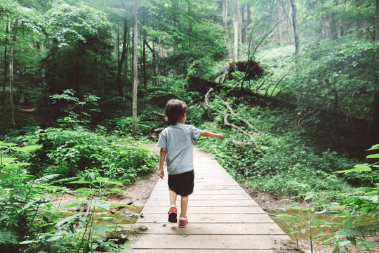 child hikes on path in woods