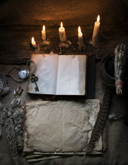 Magic fairytale table in the hut with window to the garden with open ancient book and burning candles