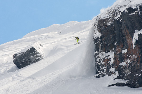 Extreme skier jumping off a snow covered rock
