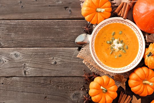 Autumn pumpkin soup, overhead table scene on a rustic wood background