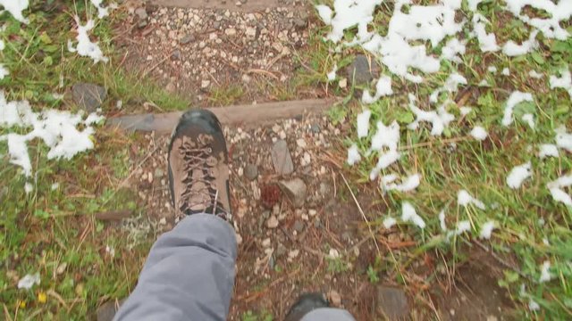 POV 4k shot of male legs in trekking boots walking down Adolf Munkel Trail in the Dolomites on a late autumn or early winter cloudy day. Healthy lifestyle, travel concept, hiking experience.